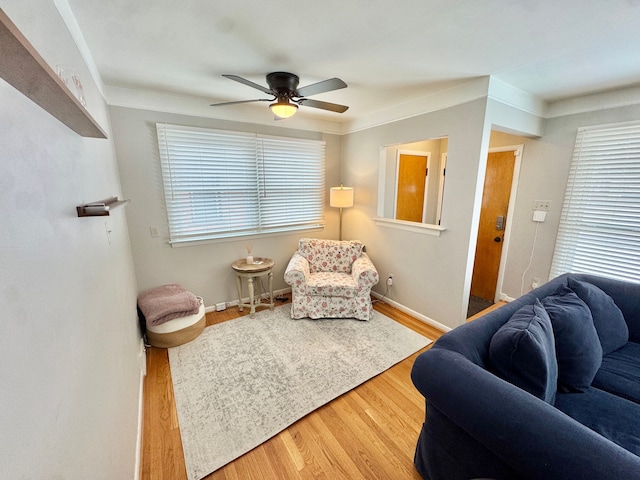 sitting room featuring wood-type flooring, crown molding, and ceiling fan