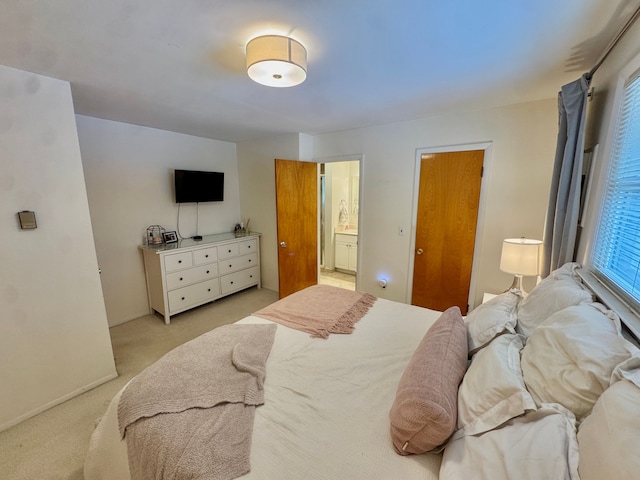 bedroom with ensuite bath and light carpet