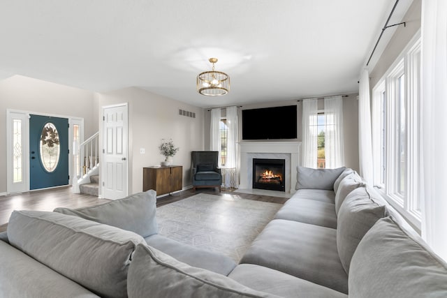 living room featuring hardwood / wood-style flooring, a high end fireplace, and a notable chandelier