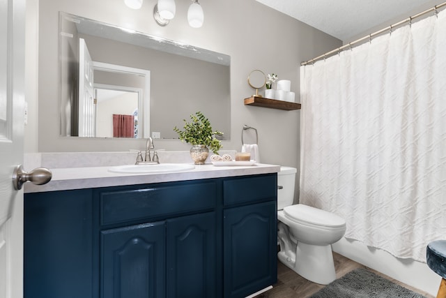 full bathroom featuring shower / bathtub combination with curtain, hardwood / wood-style floors, vanity, a textured ceiling, and toilet