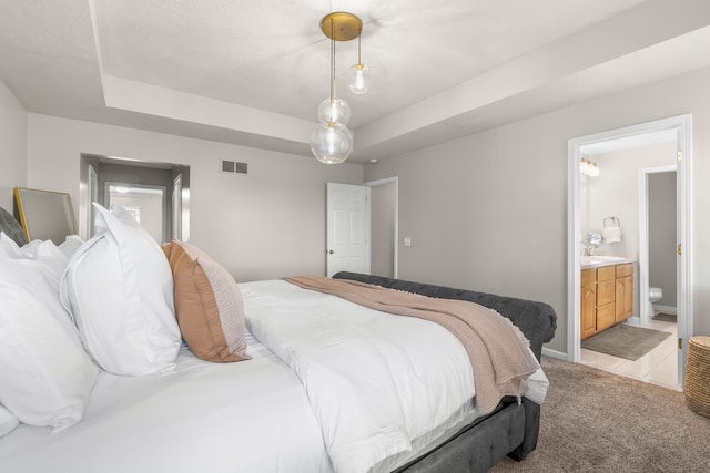 bedroom with light carpet, connected bathroom, a tray ceiling, and sink