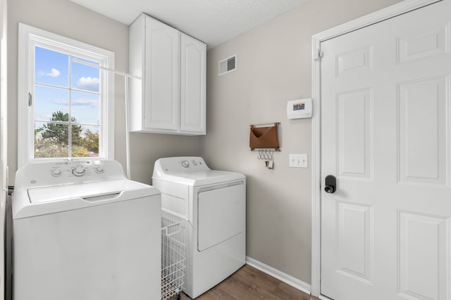 laundry area with cabinets, separate washer and dryer, dark hardwood / wood-style floors, and a textured ceiling