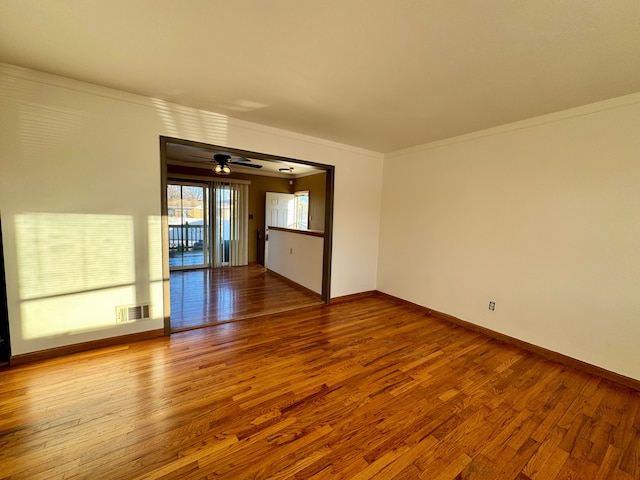 empty room featuring ceiling fan, ornamental molding, and wood-type flooring