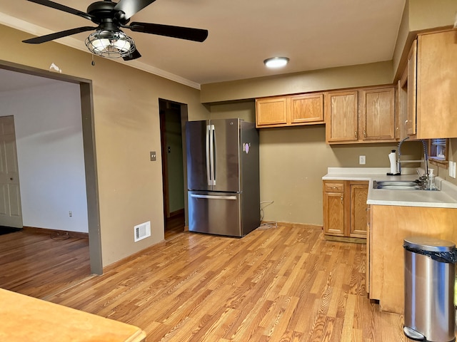 kitchen with sink, stainless steel fridge, ornamental molding, ceiling fan, and light hardwood / wood-style floors