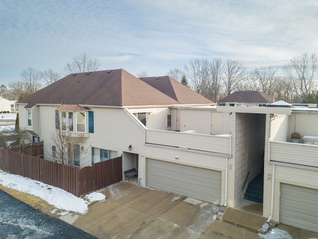 snow covered back of property featuring a garage