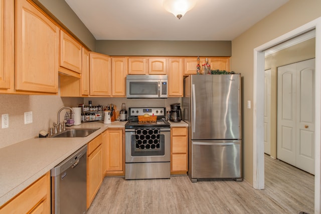 kitchen with stainless steel appliances, sink, light brown cabinets, and light hardwood / wood-style flooring