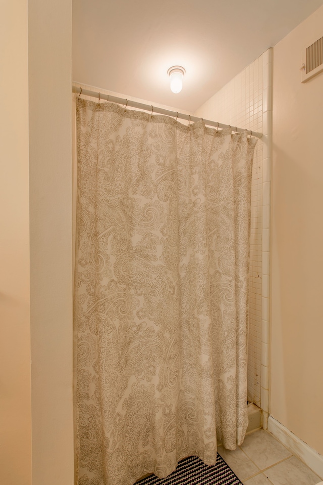 bathroom with curtained shower and tile patterned flooring