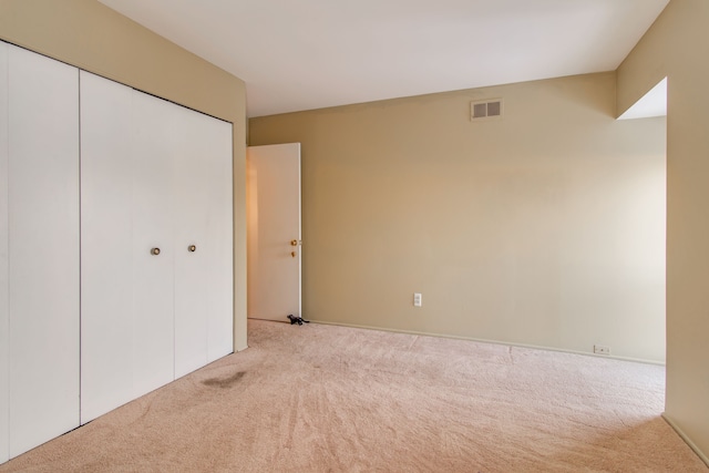 unfurnished bedroom with a closet and light carpet