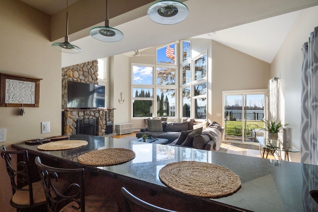 dining space with a stone fireplace and high vaulted ceiling