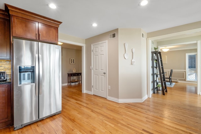 kitchen featuring backsplash, stainless steel fridge with ice dispenser, and light wood-type flooring