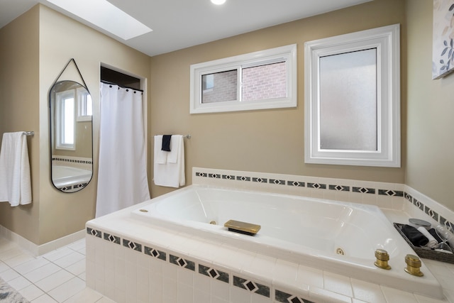 bathroom featuring a skylight, tile patterned floors, and tiled bath