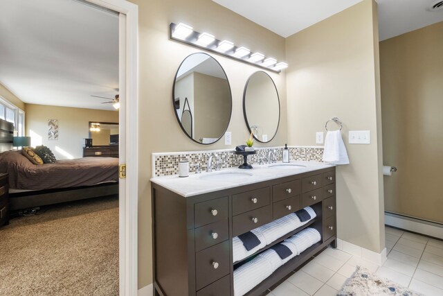 bathroom with ceiling fan, tile patterned flooring, backsplash, a baseboard heating unit, and vanity