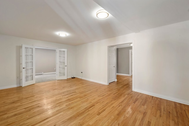 empty room with a baseboard heating unit, light hardwood / wood-style flooring, and french doors