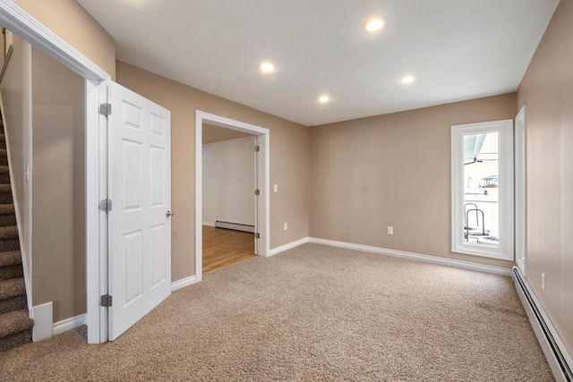 carpeted spare room featuring a baseboard heating unit