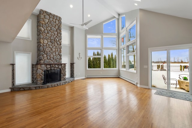 unfurnished living room with a fireplace, high vaulted ceiling, beam ceiling, and light wood-type flooring