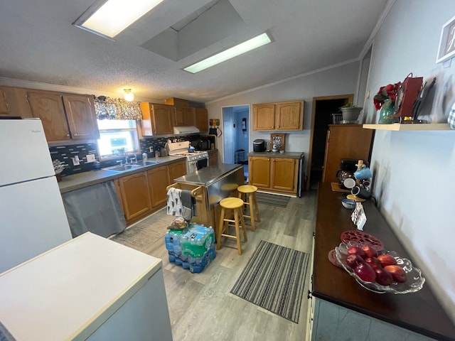 kitchen with white appliances, light hardwood / wood-style flooring, ornamental molding, a kitchen island, and vaulted ceiling