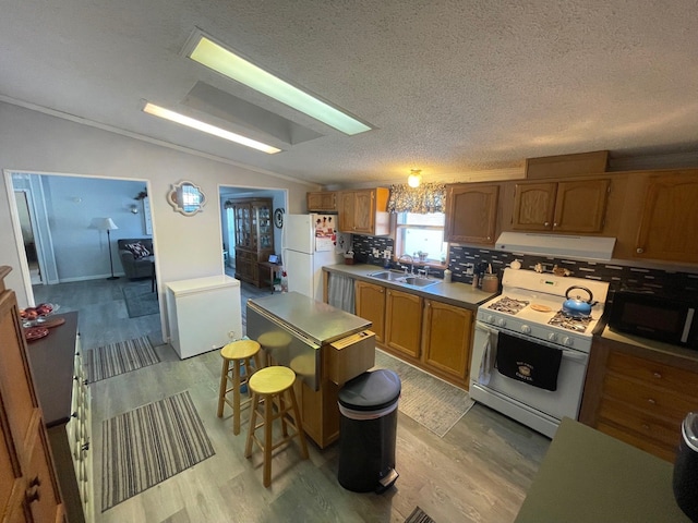 kitchen featuring lofted ceiling, sink, white appliances, light hardwood / wood-style flooring, and range hood