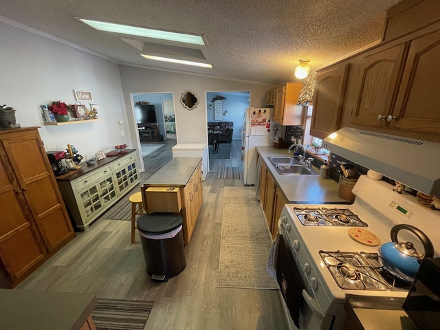 kitchen with lofted ceiling, sink, white appliances, a textured ceiling, and light hardwood / wood-style flooring