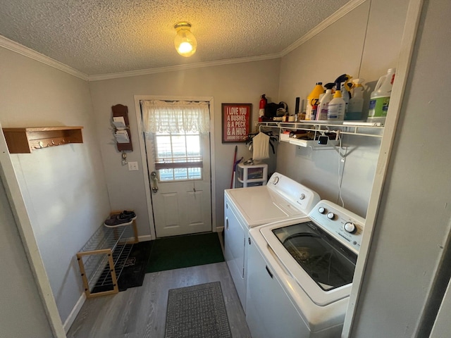 clothes washing area featuring crown molding, a textured ceiling, washing machine and clothes dryer, and hardwood / wood-style flooring