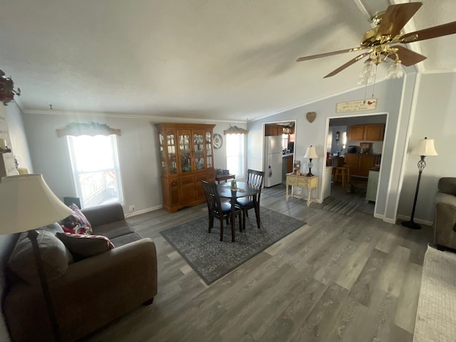 dining area with ornamental molding, wood-type flooring, and vaulted ceiling