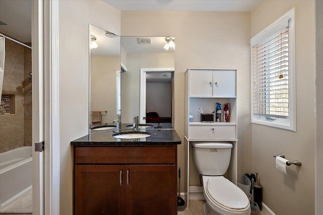 full bathroom with tiled shower / bath, vanity, and toilet