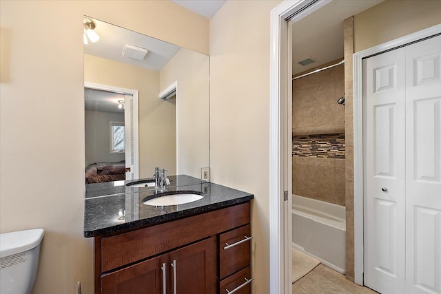 full bathroom with vanity, tiled shower / bath, and toilet