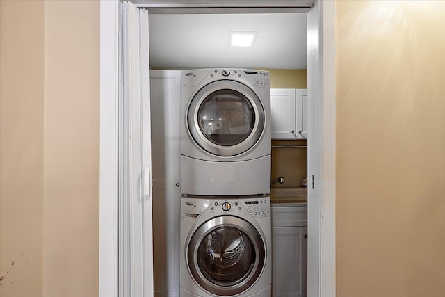 washroom with cabinets and stacked washer / dryer