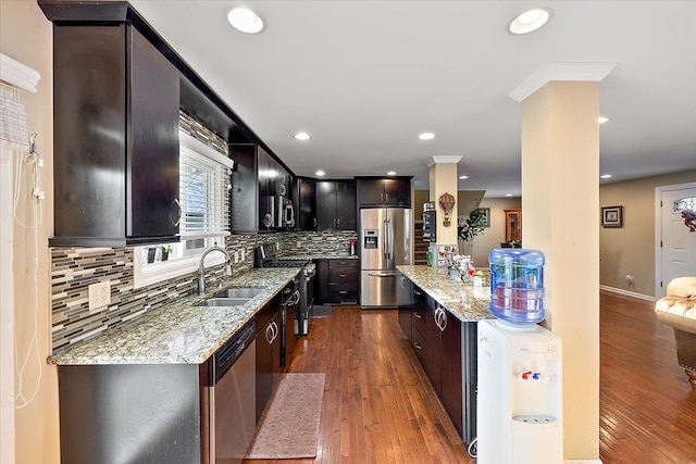 kitchen featuring appliances with stainless steel finishes, sink, dark hardwood / wood-style flooring, decorative backsplash, and light stone countertops