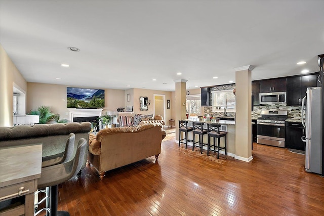 living room with dark wood-type flooring, sink, and ornate columns