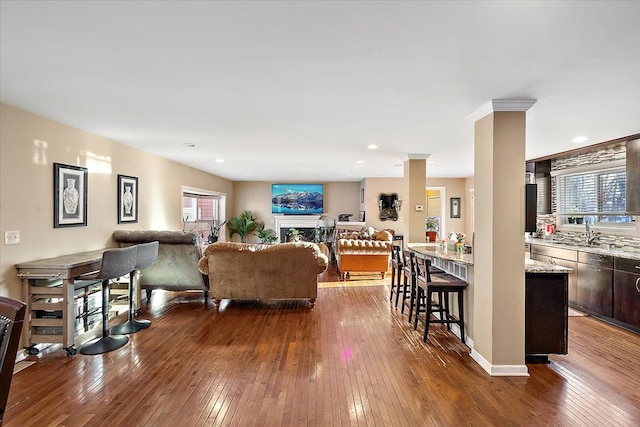 living room with ornate columns, dark hardwood / wood-style floors, and sink