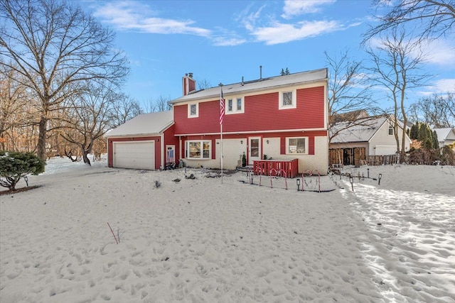 snow covered rear of property featuring a garage