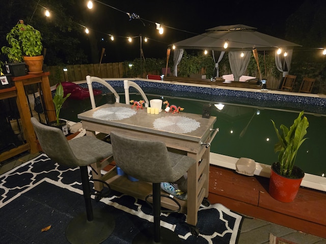 pool at twilight featuring a bar and a gazebo