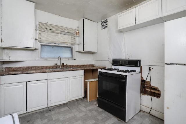 kitchen with gas range, white cabinetry, white refrigerator, and sink