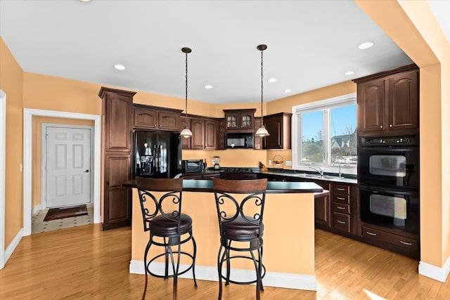 10587 Lighthouse, South Lyon, MI 48178 - kitchen featuring black appliances, dark brown cabinets, a kitchen island, a sink, and a kitchen bar