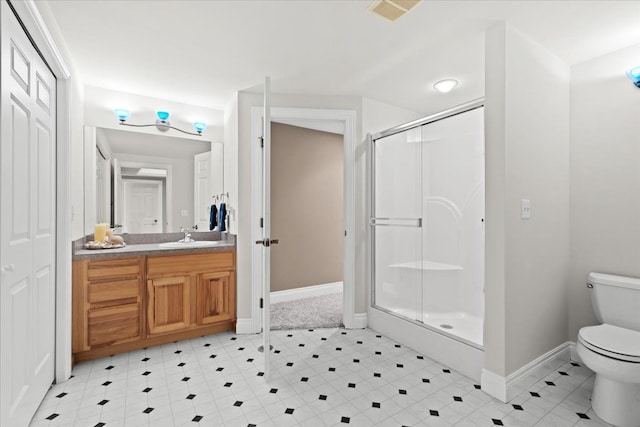 bathroom featuring a shower with door, vanity, and toilet