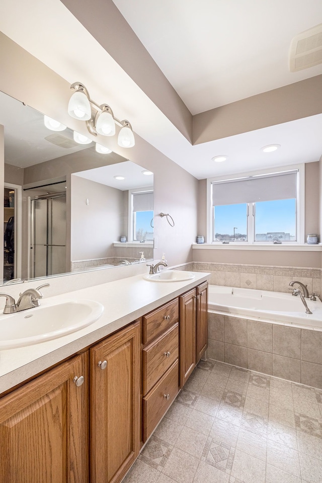 bathroom featuring vanity, a healthy amount of sunlight, and tiled bath