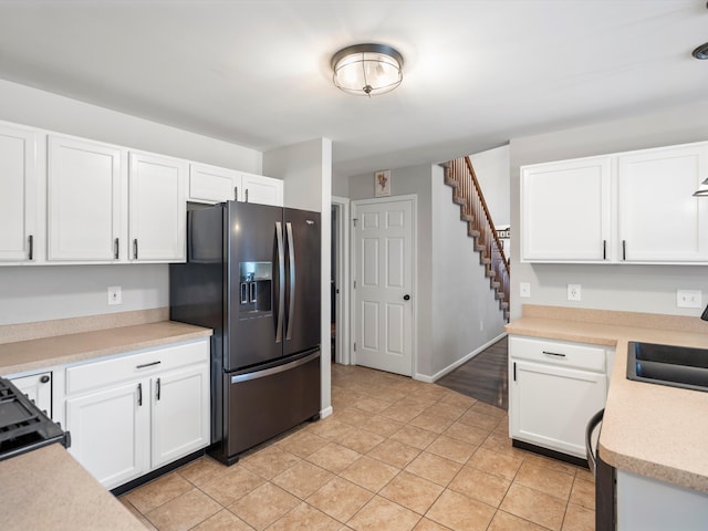 kitchen featuring white cabinetry, sink, light tile patterned floors, and black refrigerator with ice dispenser