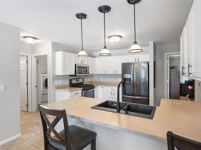 kitchen featuring sink, kitchen peninsula, stainless steel appliances, washer / clothes dryer, and white cabinets