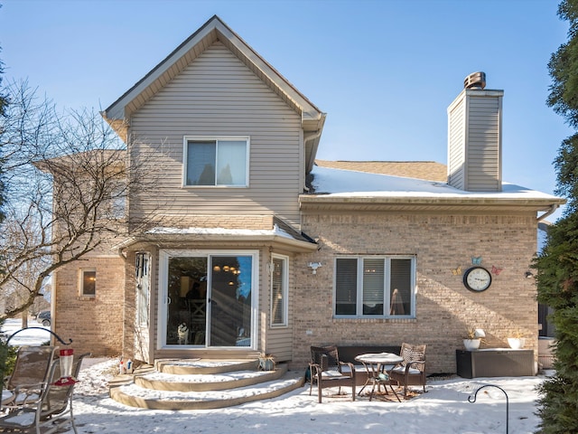 snow covered back of property with a patio area