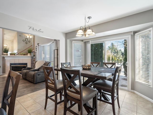 tiled dining room featuring a tiled fireplace and a chandelier