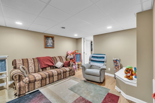 living room with a paneled ceiling and light hardwood / wood-style flooring