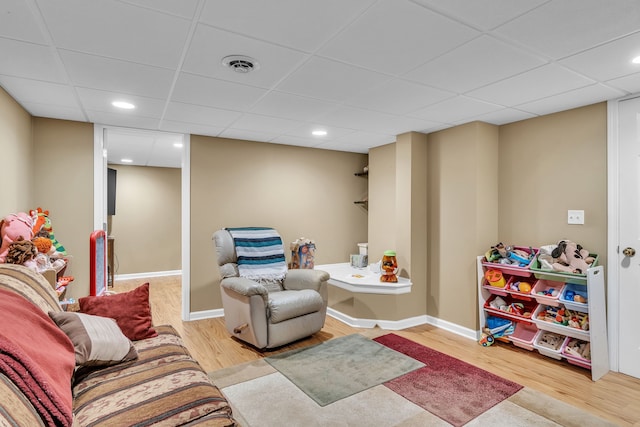 playroom with a paneled ceiling and light hardwood / wood-style flooring