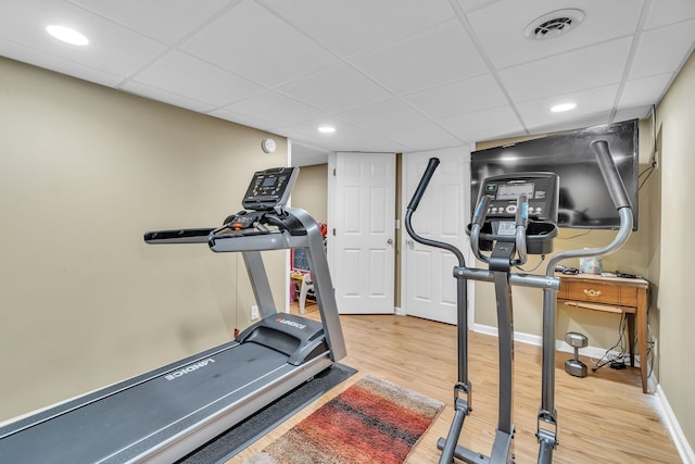 exercise room featuring wood-type flooring and a drop ceiling