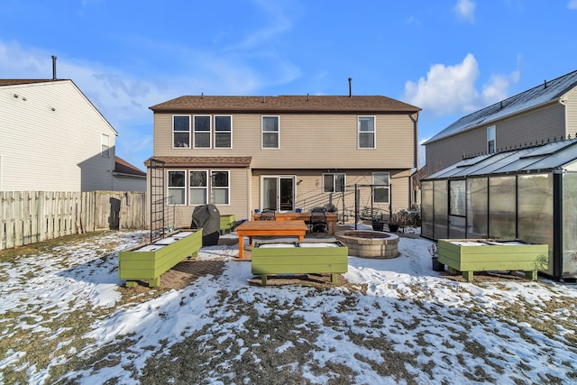 snow covered rear of property featuring an outdoor structure, a deck, and an outdoor fire pit