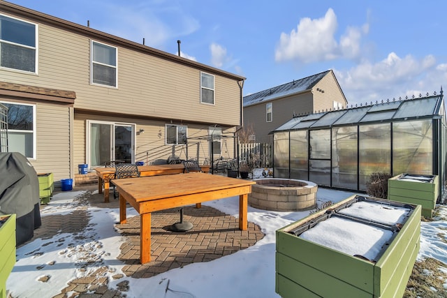 snow covered back of property featuring an outbuilding and an outdoor fire pit