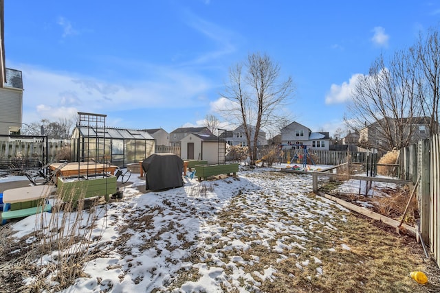 yard layered in snow featuring a storage shed and a playground