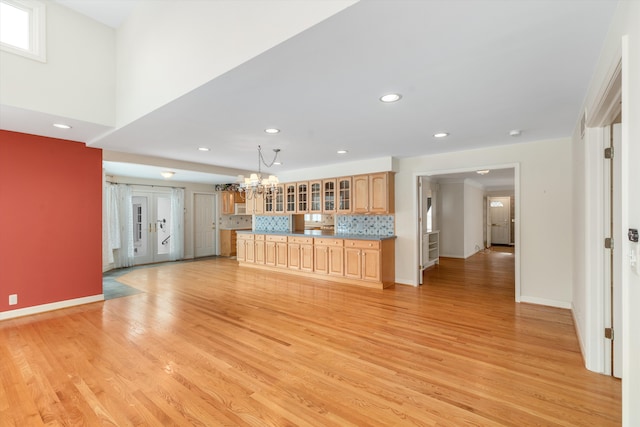 unfurnished living room with a chandelier and light wood-type flooring