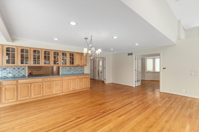 kitchen featuring a notable chandelier, hanging light fixtures, light hardwood / wood-style flooring, and backsplash