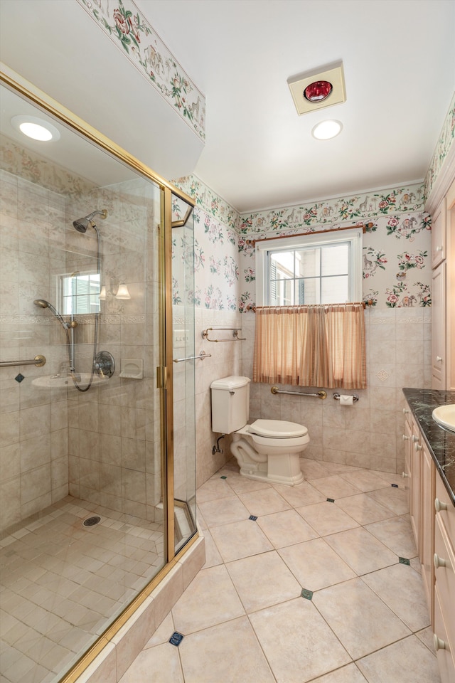 bathroom featuring a shower with shower door, tile walls, tile patterned flooring, vanity, and toilet