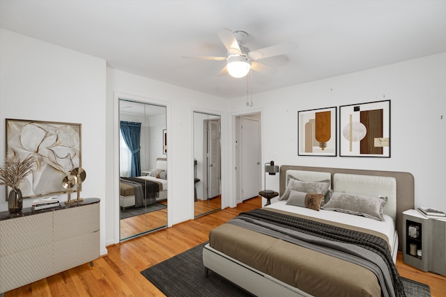 bedroom with ceiling fan, light wood-type flooring, and two closets